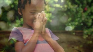 Parlak güneşli bir günde ormanda dua eden Afrikalı-Amerikalı küçük bir çocuğun dijital bileşimi