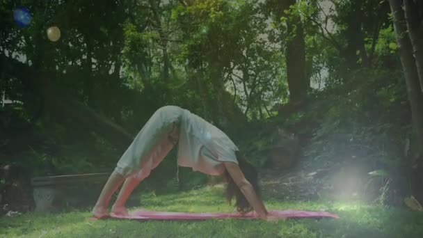在公园做瑜伽的女人的侧视图 可以看到散景灯在前景中坠落 — 图库视频影像