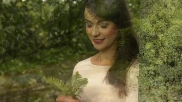 一个白种妇女拿着树叶在森林里闻闻的侧视图 — 图库视频影像