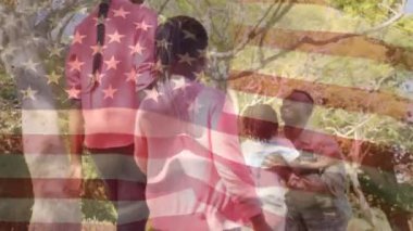 Bir parkta askeri üniformalı babası ile yeniden biraraya gelen bir Afrikalı-Amerikalı ailenin dijital kompozit ve bir Amerikan bayrağı sallayarak arka plan