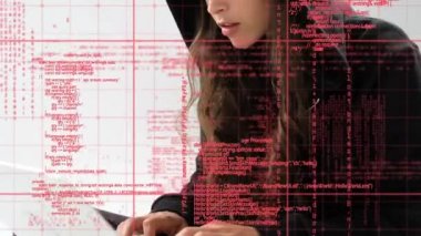Bir dizüstü bilgisayar ve ön planda kullanırken bir başlık giyen genç bir Kafkas kadın hacker dijital kompozit kodları gösterir.