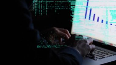 Ekranda grafikler ve ekranda hareket eden program kodları ile bir dizüstü bilgisayar kullanan bir hacker dijital kompozit