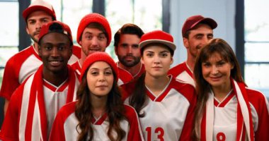 Front view of a group of sports fans wearing white and orange jerseys cheering 4k