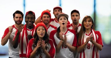 Front view of a group of sports fans wearing red and white jerseys cheering loudly 4k