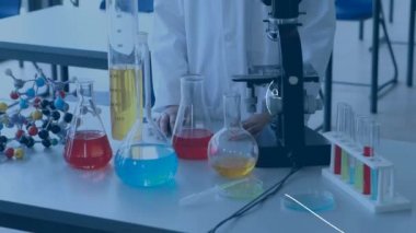 Ön planda çalışan kimyasallar ve ekipman ve denklemler ile bir tablonun önünde duran bir kimya öğrencisinin dijital kompozit