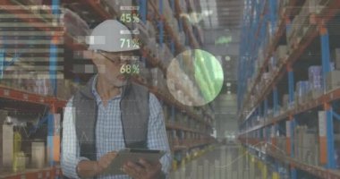 Front view of a male Caucasian worker wearing a hard hat writing on a clipboard while checking packages on shelves. Digital animation of graphs and statistics are running in the foreground 4k