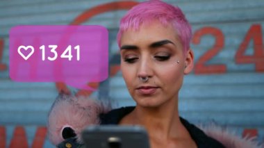 Arka planda akıllı telefon kullanarak pembe saçlı ve yüz piercing ile beyaz bir kadın gösterirken bir kalp ve artan numaraları ile bir mesaj kabarcık simgesi dijital olarak oluşturulan animasyon.