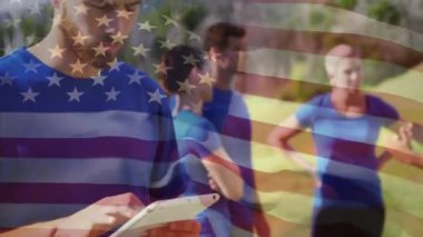 Amerikan bayrağı arka planda sallanırken tablet kullanan beyaz bir adamın dijital bileşimi