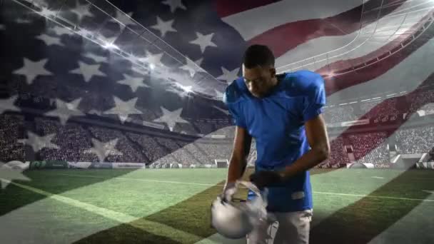 彼のヘルメットを着用したアフリカ系アメリカ人サッカー選手のデジタルコンポジットとフィールドスタジアムの背景に手を振るアメリカの旗 — ストック動画