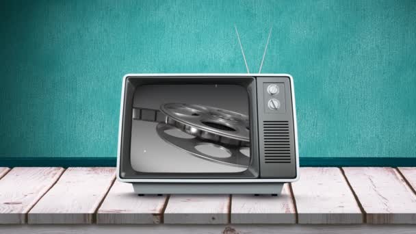 木製のテーブルの上のテレビのデジタルアニメーションと 画面上のフィルムロールを持つ緑色の背景 — ストック動画