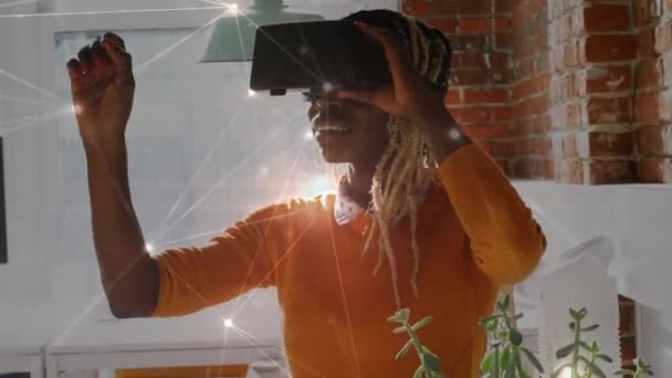 前景に接続されたドットと線を持つバーチャルリアリティヘッドセットを身に着けているアフリカ系アメリカ人女性のデジタルコンポジット — ストック動画
