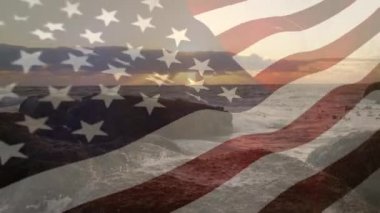 Gün batımında ön planda sallanan bir Amerikan bayrağı ile kayalık bir kıyıya sıçrayan dalgaların dijital bileşimi