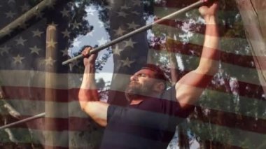 Ön planda sallanan bir Amerikan bayrağı ile parkta pull up yapan bir Amerikalı adamın dijital kompozit