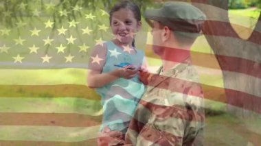 O ön planda sallayarak bir Amerikan bayrağı ile bir mini bayrak tutarken kızını taşıyan bir Amerikan askeridijital kompozit