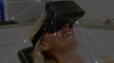 Ön planda bağlı çizgiler ve noktalarla sanal gerçeklik kulaklığı takarken yatan beyaz bir kadının dijital bileşimi