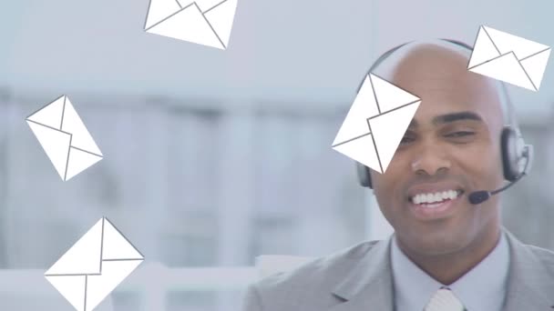 前景に電子メールアイコンが落ちているヘッドセットで話すアフリカ系アメリカ人ビジネスマンのデジタルコンポジット — ストック動画
