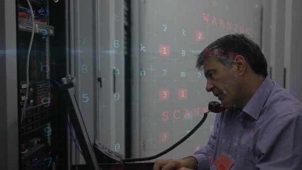 一个成年白种男性技术人员在与电话通话时在服务器塔上做维护的侧视图 随机字母 数字和有关网络攻击的文字在屏幕上移动 — 图库视频影像