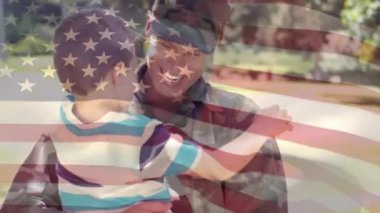 Ön planda sallanan bir Amerikan bayrağı ile parkta oğluna büyük bir kucaklama veren bir Amerikan kadın asker dijital kompozit