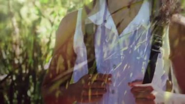 Uzun otlarla dolu bir ön plan ile vahşi doğada bir sırt çantası giyen beyaz bir kadının dijital kompozit