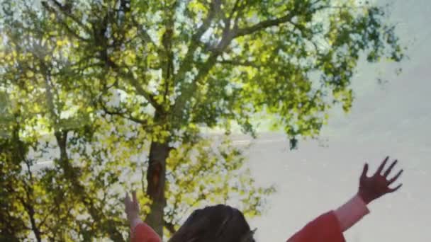 明るい晴れた日に木の下で陽気に回転する小さな白人の女の子のデジタルコンポジット — ストック動画