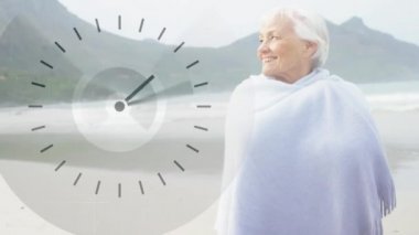 Sahilde gülümseyen battaniye giyen yaşlı beyaz bir bayanın dijital kompoziti