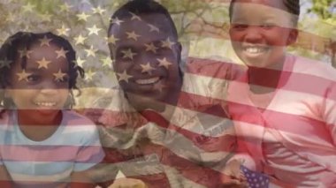 Ön planda sallanan bir Amerikan bayrağı ile parkta iki çocuğu ile gülümseyen bir Afrikalı Amerikalı askerin dijital kompozit
