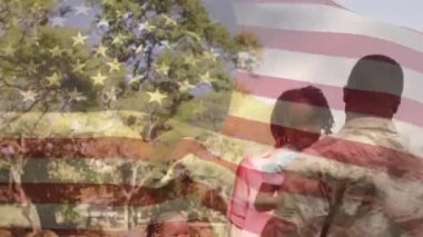 Ön planda sallanan Amerikan bayrağı olan bir parkta çocuklarını taşıyan Afrikalı-Amerikalı bir askerin dijital bileşimi