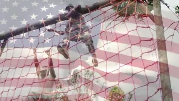 两名美国士兵从货网上爬下来的数字合成物 一面美国国旗在前景中飘扬 — 图库视频影像