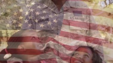 Ön planda sallanan bir Amerikan bayrağı ile iki kızı tutan bir kadın Afrikalı Amerikalı askerin dijital kompozit