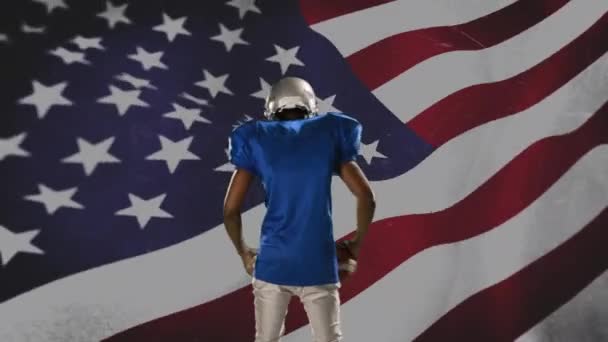 背景に手を振るアメリカの旗でハイプアップアフリカ系アメリカ人のサッカー選手の背面図 — ストック動画