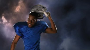 Arka plan şimşek ile kara bulutlar gösterirken Amerikan futbolu bir Afrikalı-Amerikalı oyuncu sinirleniyor dijital kompozit