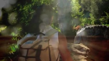 Bokeh ışık efektleri ile ormanda bir günlük üzerinden tırmanma bir kadın yürüyüşçü dijital kompozit