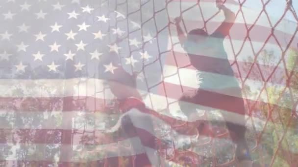 前景に手を振るアメリカの旗で貨物網を登る2人の女性のデジタルコンポジット — ストック動画