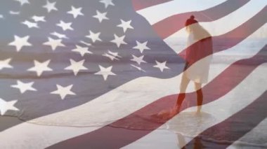 Ekranda Amerikan bayrağı dalga iken plajda duran bir kadının dijital kompozit