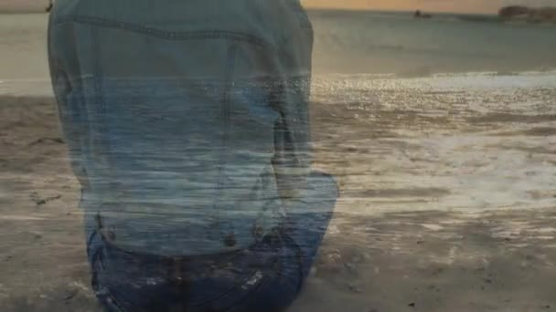 Denizdalgalarının Arka Planı Ile Gün Batımı Sırasında Plajda Oturan Bir — Stok video