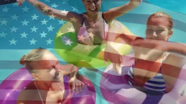 7月4日 在泳池中用五颜六色的漂浮物 用五颜六色的浮子 而美国国旗在背景中挥舞 这是白种妇女的数字合成 — 图库视频影像