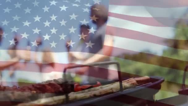 多様な友人のグループが7月4日の飲み物やバーベキューを背景に祝っている間 アメリカの旗のデジタルコンポジット — ストック動画