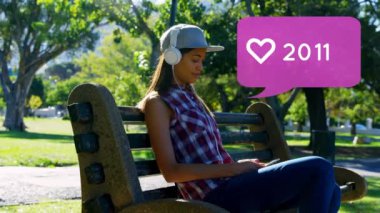 Bir parkta bankta otururken müzik dinleyen Beyaz kadının dijital bileşimi. Ön planda sosyal medya için sayısı artan bir kalp simgesi