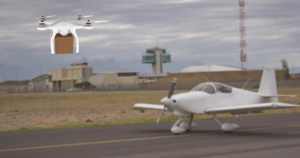 飛行機4Kの前でホバリングしながら茶色の箱を運ぶ白いドローンのデジタルアニメーション — ストック動画
