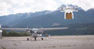 Arka planda bir uçak ve dağlar ile bir havaalanında vurgulama sırasında kahverengi bir kutu taşıyan beyaz drone dijital animasyon. 4k