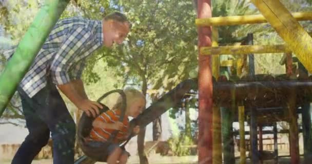 Composto Digital Pai Caucasiano Empurrando Filho Balanço Playground Sorrindo Enquanto — Vídeo de Stock