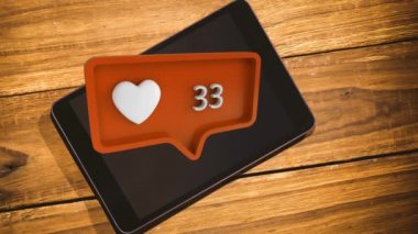 Ahşap bir masanın üstüne bir Tablet dijital kompozit ve kalp simgesi ve artan sayılar sosyal medya ile turuncu mesaj kabarcık