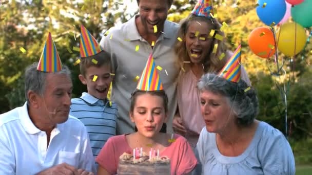 一个白人家庭的数码合成产品在户外庆祝一个小女孩吹灭生日蛋糕上的蜡烛 而金粉却掉进了银幕 — 图库视频影像