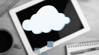 Kareler üzerinde farklı simgelerin beyaz bir buluta doğru hareket eden dijital animasyonu, arka planda dijital tabletli bir fincan kahve içeren bir masa gösterilirken,.