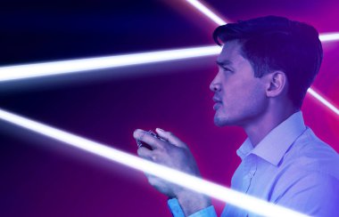 Turkuaz ve mor arka plana karşı video oyunu oynayan genç işadamının yan görünümü