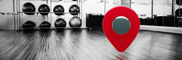 Close-up of map marker against large empty fitness studio with shelf of exercise balls