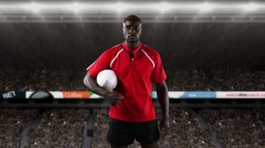 Bir top tutan ve arka planda ışıklandırılmış stadyum ile kameraya bakan bir Afrikalı-Amerikalı erkek rugby oyuncusu Animasyon