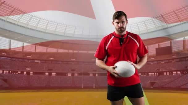 一个白人男子橄榄球运动员玩球 并期待相机与吹丹麦国旗和体育场的背景动画 — 图库视频影像