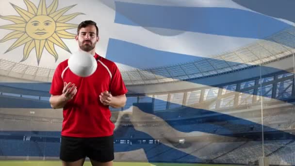 一个白人男子橄榄球运动员玩球的动画 并期待与乌拉圭和体育场的背景吹国旗相机 — 图库视频影像