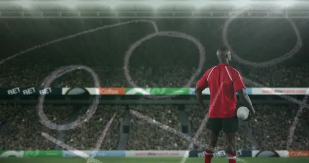 一个非裔美国男子橄榄球运动员的后视动画 他手里拿着一个球 在前台和体育场背景4K中用手绘的游戏计划环顾四周 — 图库视频影像